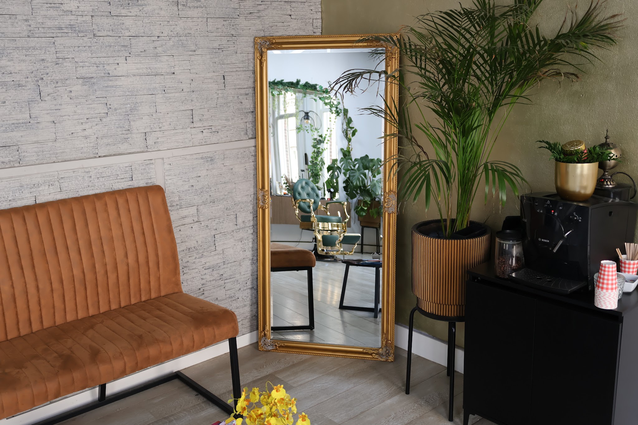 Wachthoek met cognackleurige bank, gouden spiegel en een palm