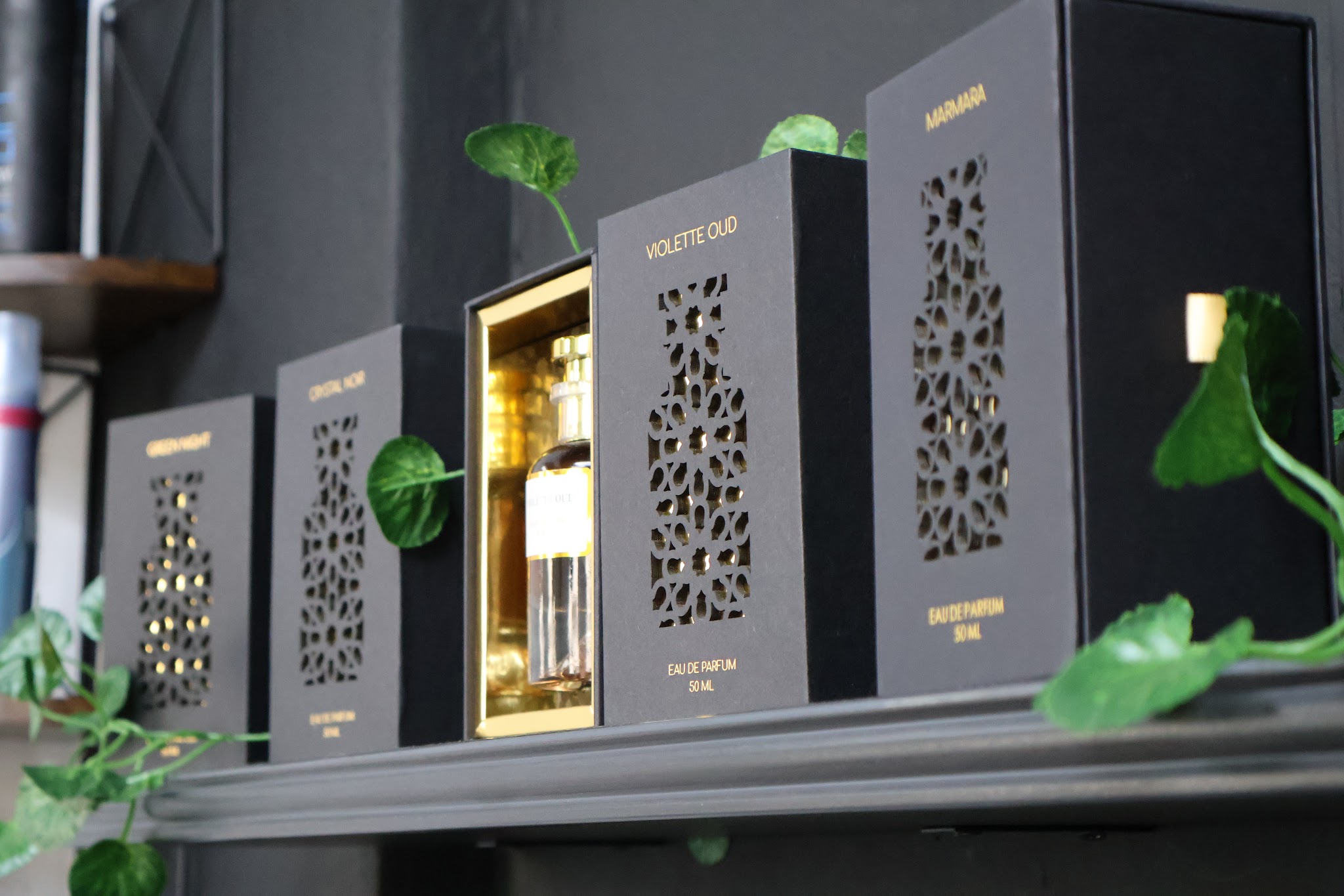Zwart-gouden parfumdozen op een plank met planten