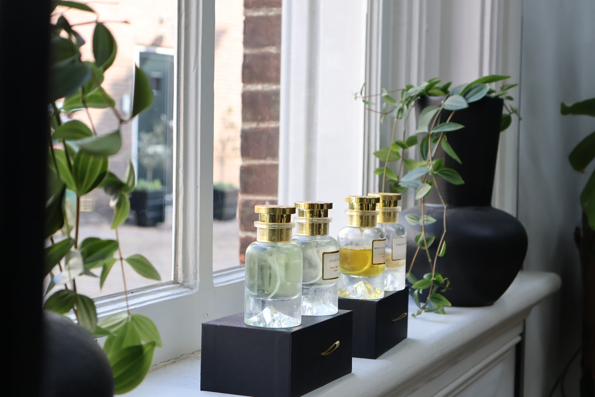 Parfumflessen met gouden doppen in de vensterbank tussen de planten