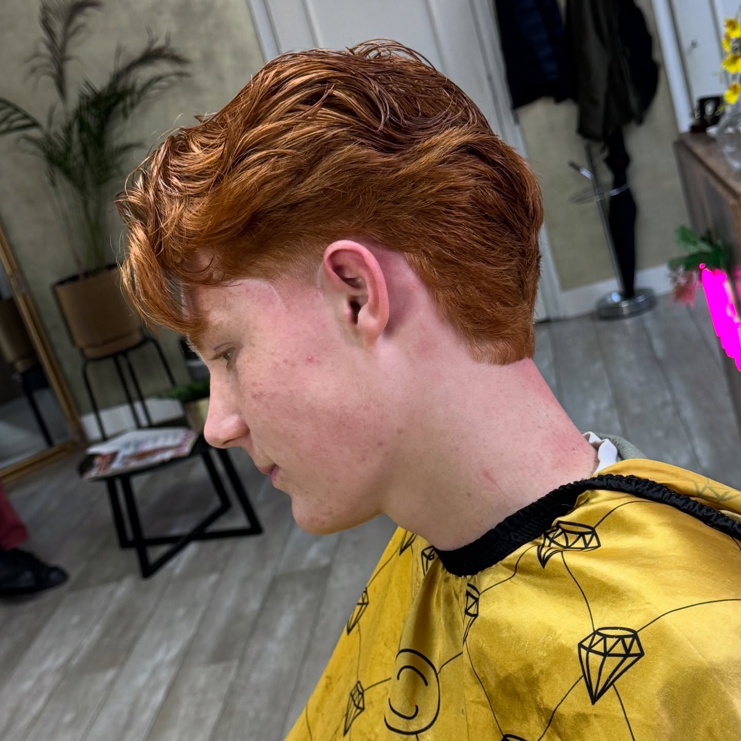 Een klant met rood haar en een frisse fade, net geknipt in de barbershop