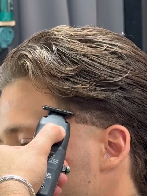 Close-up: Omar zet met de trimmer de contouren van een fade